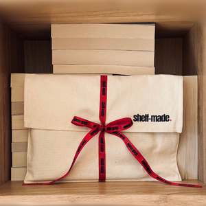 A mystery dark romance book bundle wrapped in a canvas sleeve with a red ribbon.