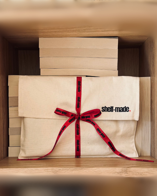 A mystery dark romance book bundle wrapped in a canvas sleeve with a red ribbon.