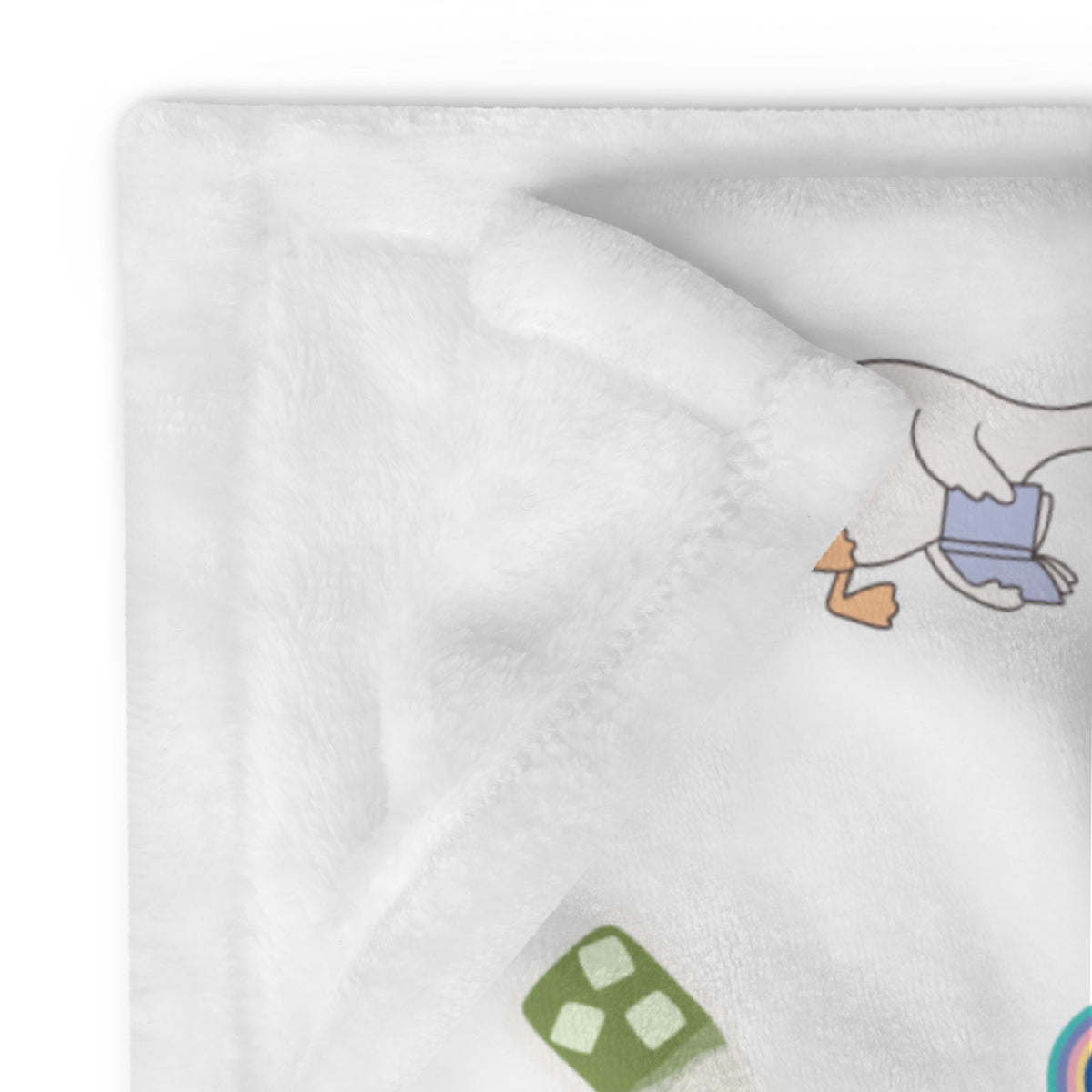 A white plush throw blanket with a cartoon goose holding a book.