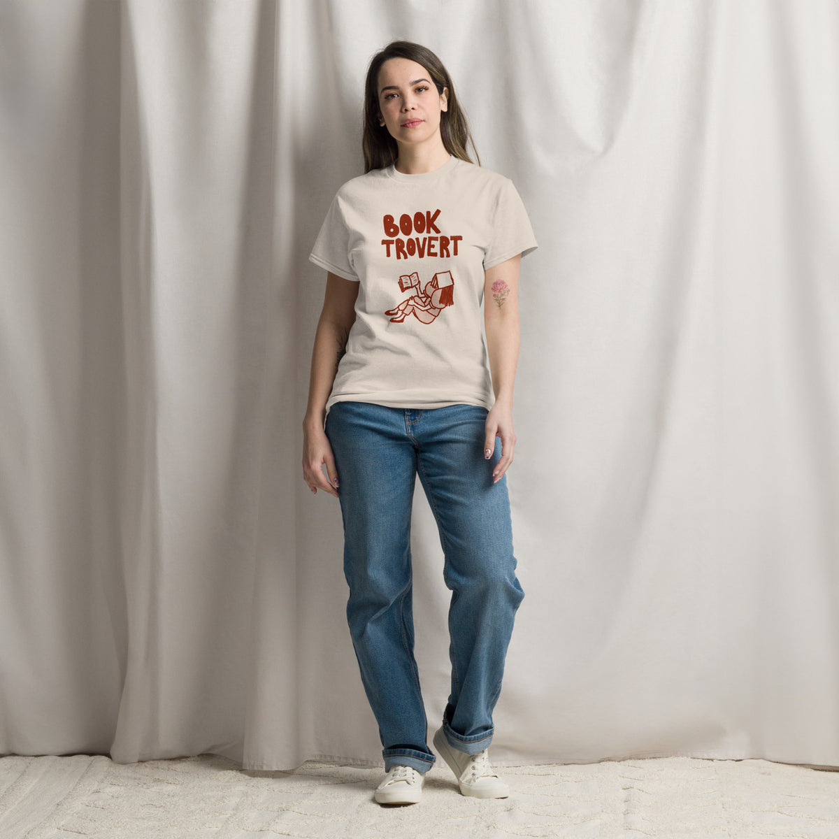 A woman wears a cream t-shirt with "Booktrovert" text and a graphic of a person reading.