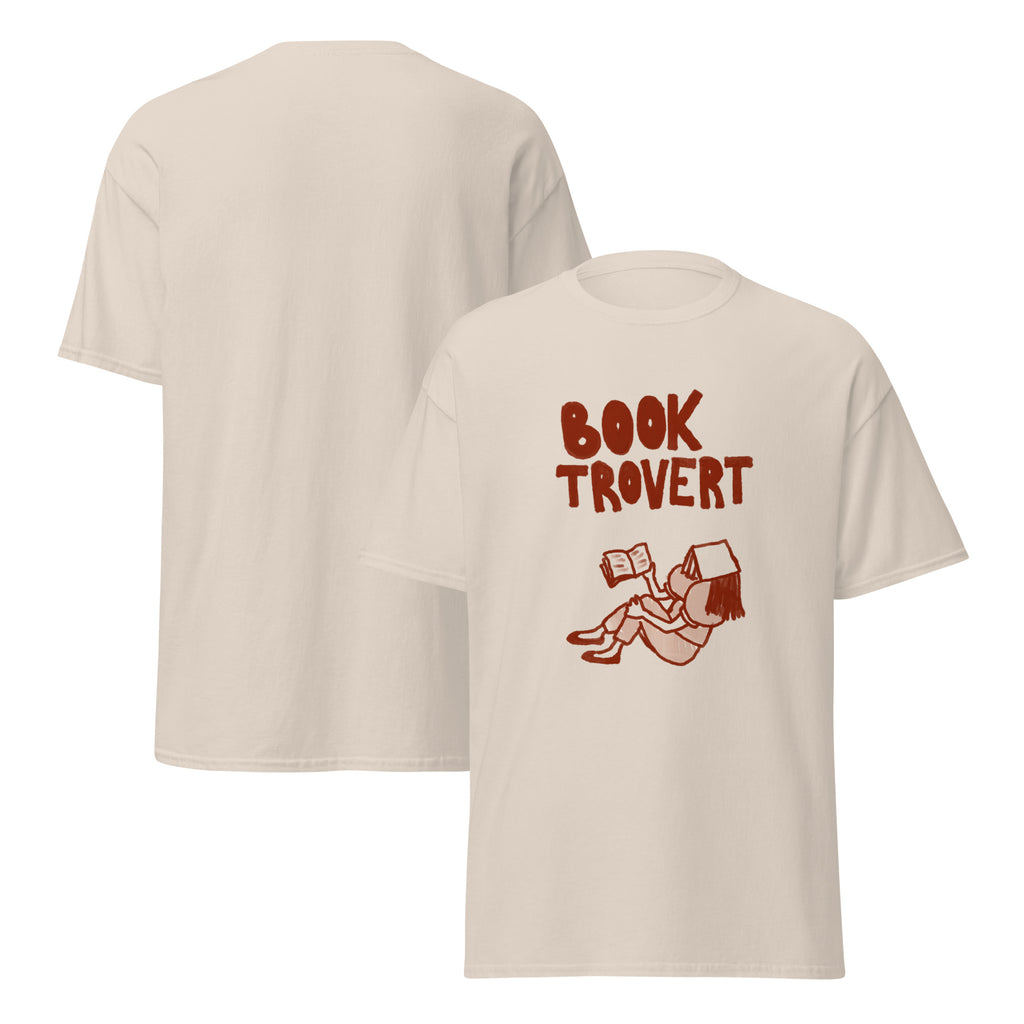 A light beige t-shirt with a graphic of a person reading and the words "BOOK TROVERT".