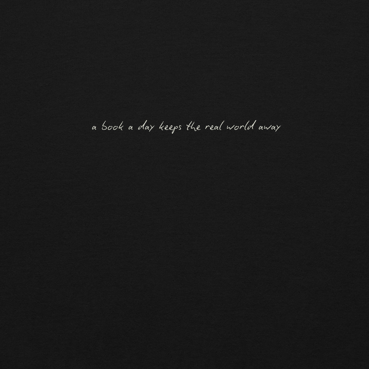 A black sweatshirt with white text that reads "a book a day keeps the real world away".