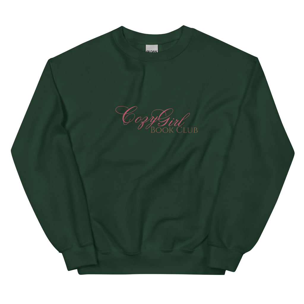 A dark green sweatshirt with "Cozy Girl Book Club" embroidered in pink script.