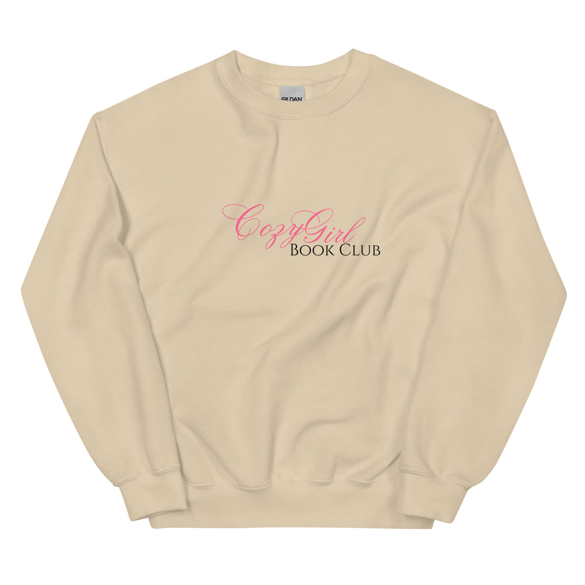 A tan crewneck sweatshirt with "Cozy Girl Book Club" printed in pink and black.