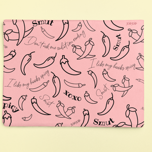 Pink wrapping paper with a pattern of black chili peppers and the words "Smut" and "I like my books spicy".