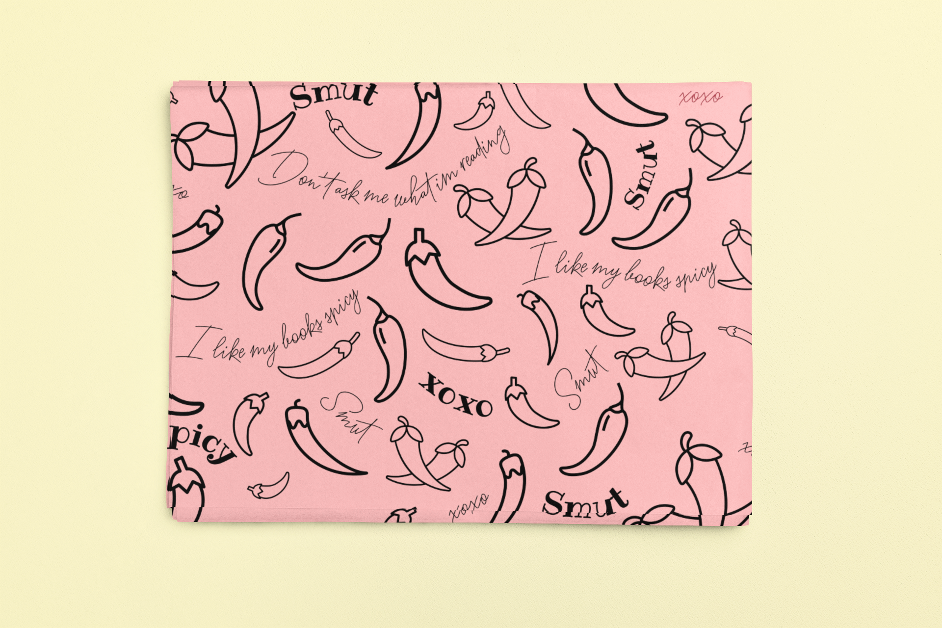 Pink wrapping paper with a pattern of black chili peppers and the words "Smut" and "I like my books spicy".
