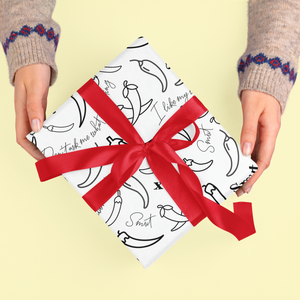 Spicy Chilli wrapping paper with red ribbon held by hands.
