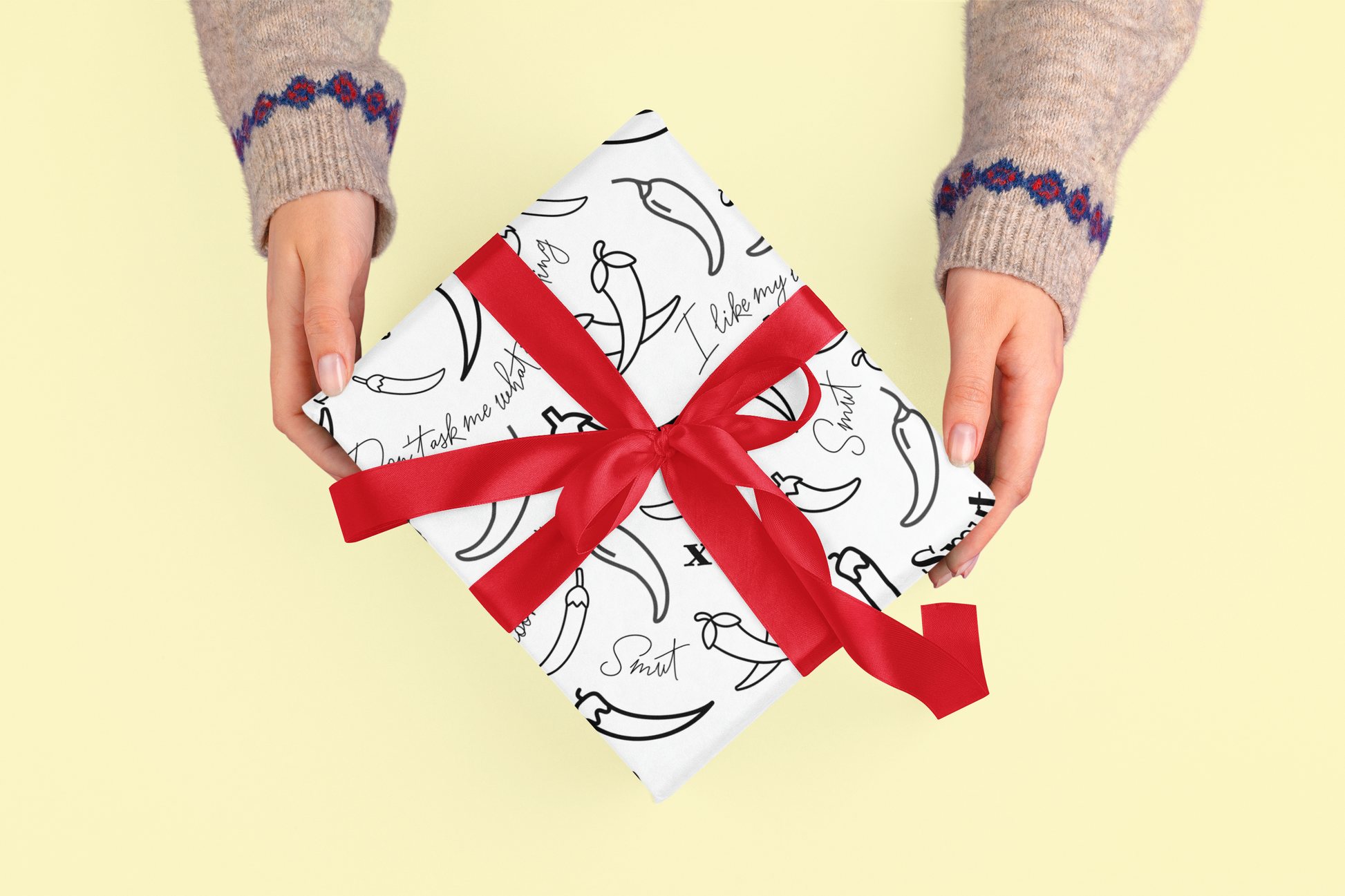 Spicy Chilli wrapping paper with red ribbon held by hands.