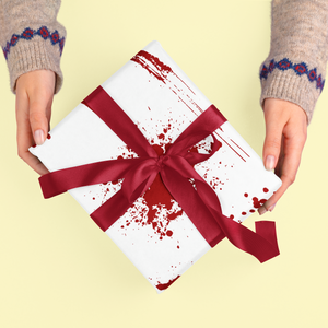 White gift wrap with red splatters and a red ribbon.