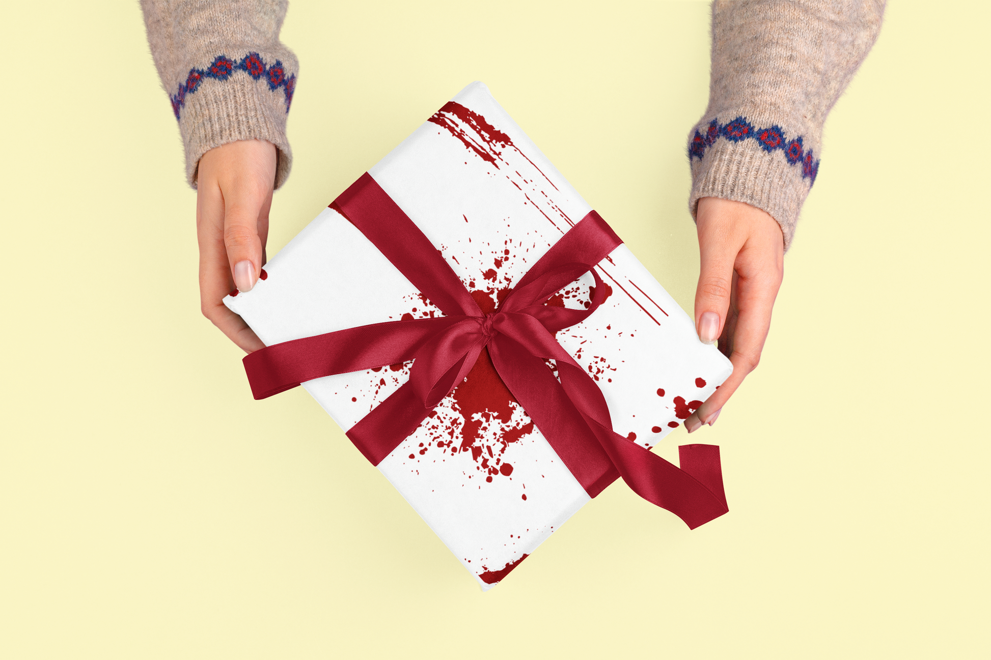 White gift wrap with red splatters and a red ribbon.