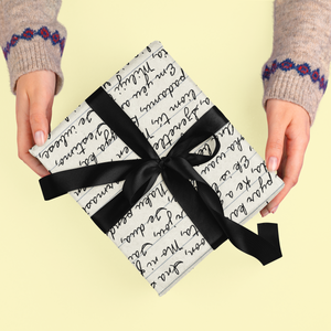 Gift wrapped in paper with handwritten script and black ribbon.