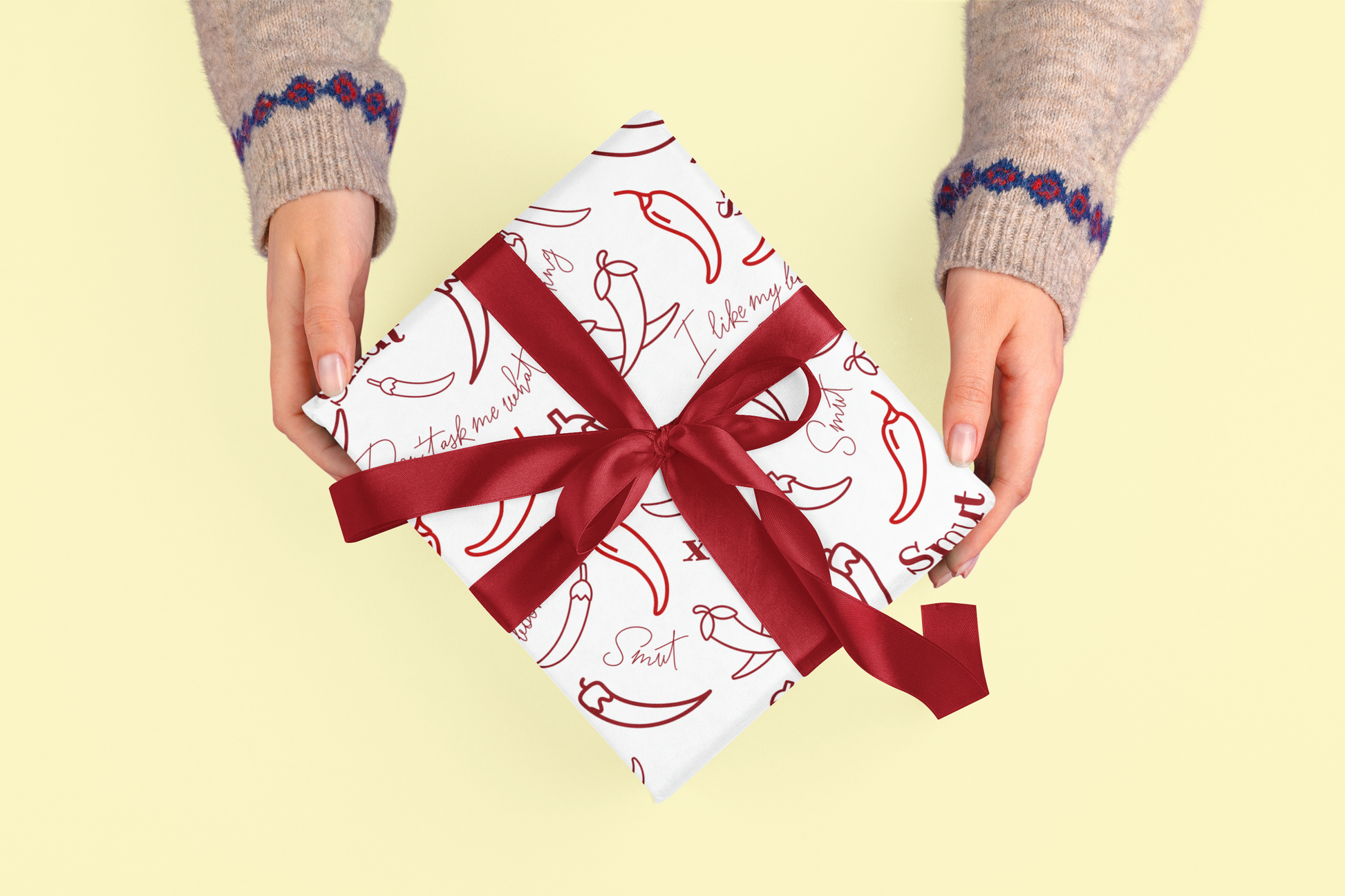Gift wrapped in paper with red chili pattern and ribbon.